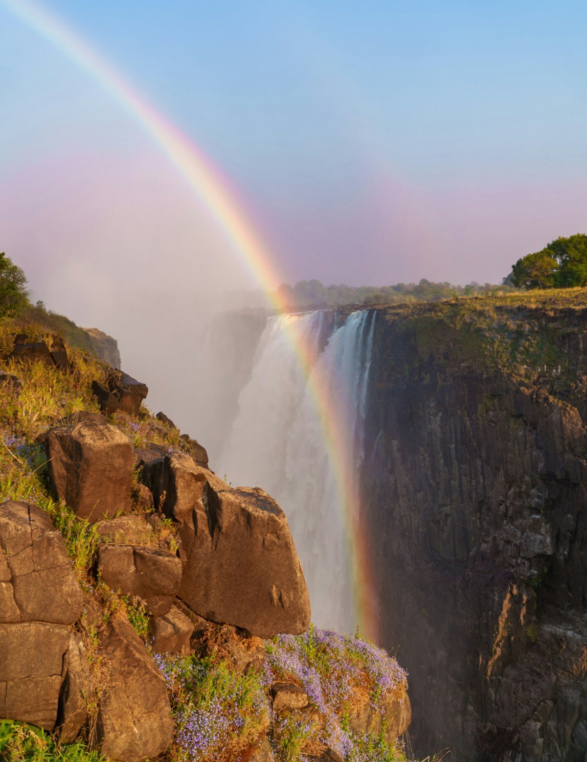 Double rainbow over Victoria Falls gorge with mist rising from the world's largest waterfall