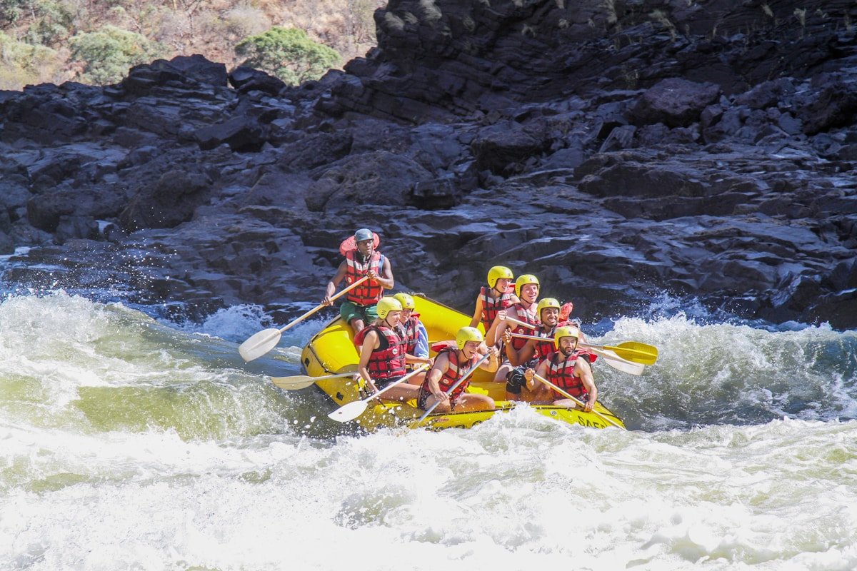 A group of paddlers in a yellow raft navigating white water rapids in the Zambezi Gorge below Victoria Falls, Zimbabwe
