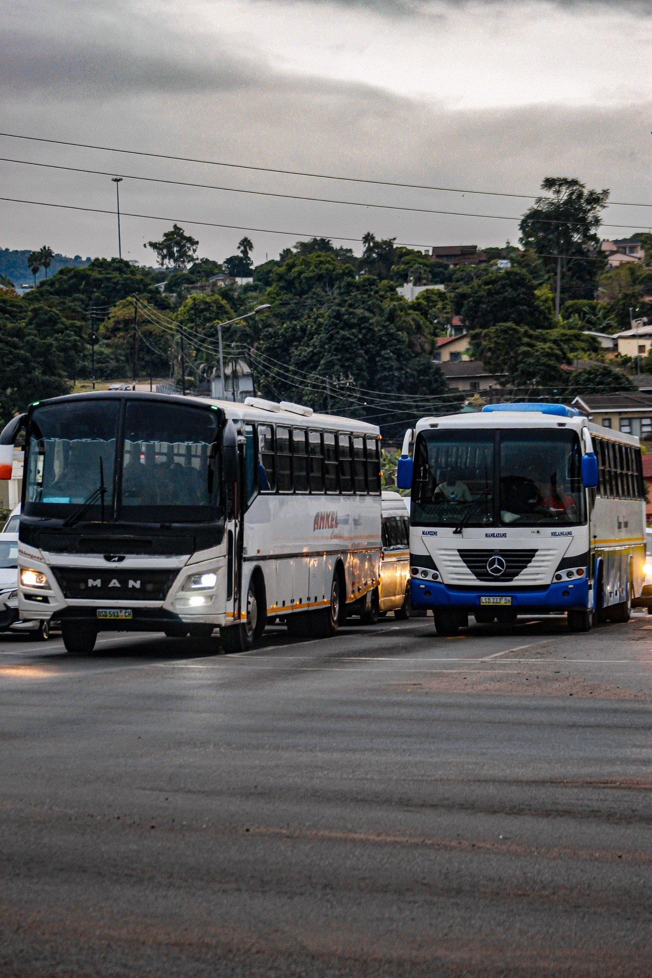 Two large buses navigating an urban street intersection in southern Africa