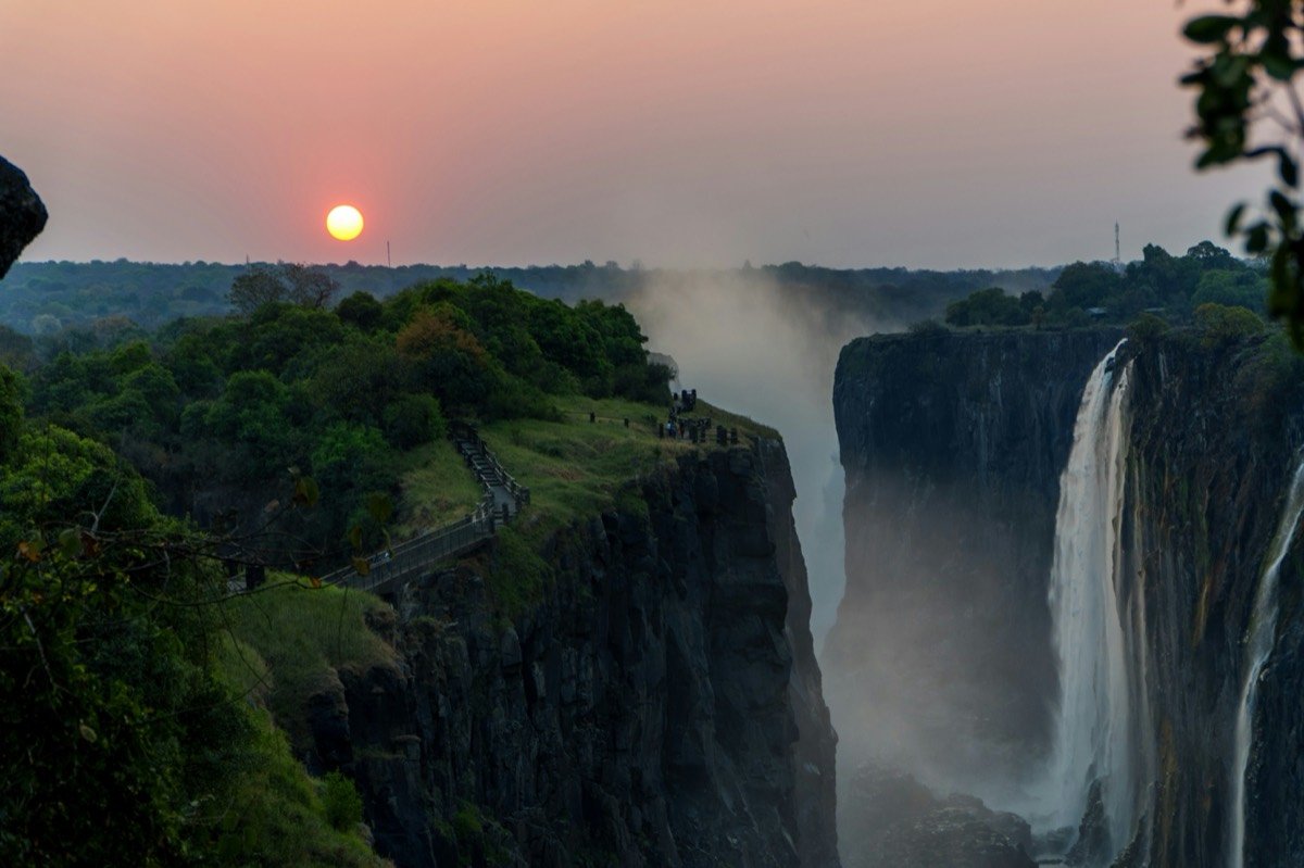 Sunset over a majestic waterfall with misty spray, Victoria Falls, Zimbabwe