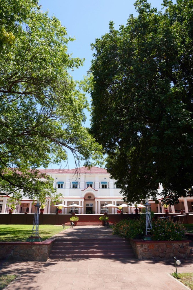 A large white building surrounded by trees on a sunny day, Victoria Falls, Zimbabwe
