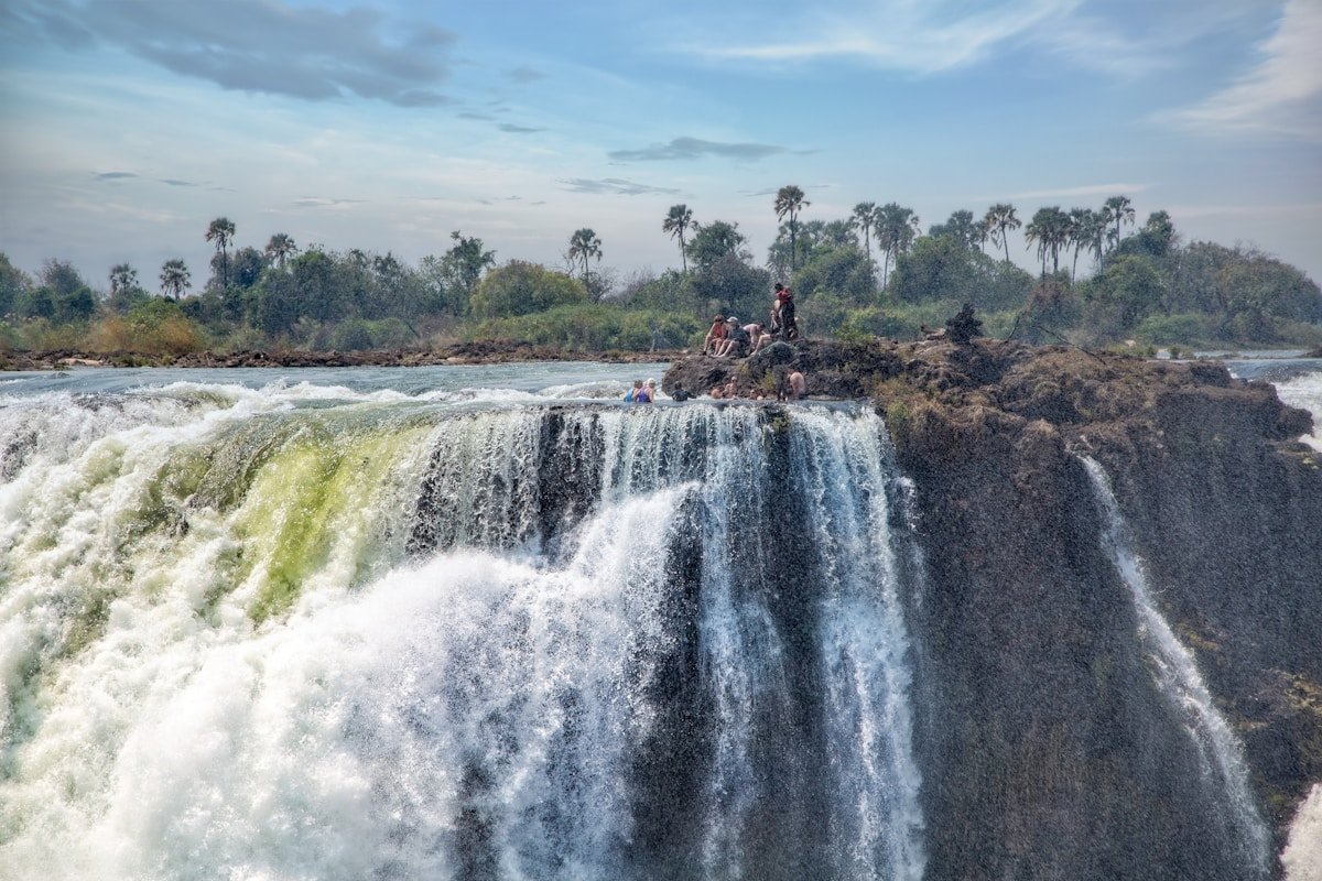 Visitors sitting at the edge of Victoria Falls above the gorge, Zimbabwe