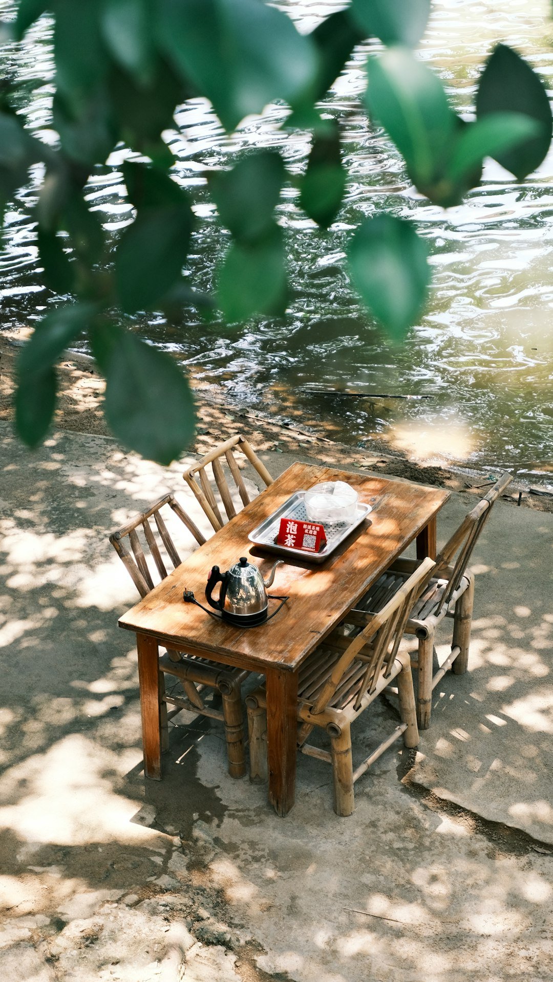 Rustic wooden table and chairs beside a river for outdoor dining at Victoria Falls, Zimbabwe
