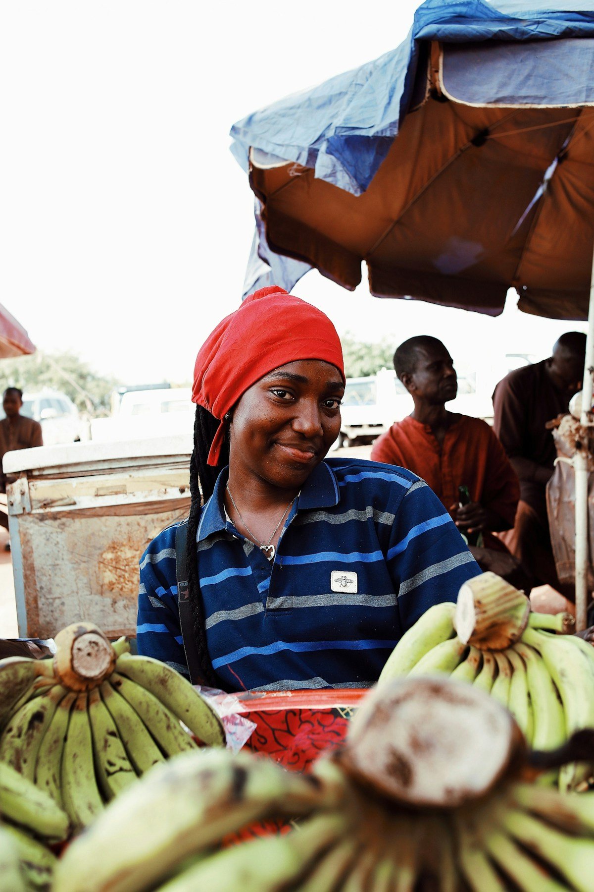 Woman vendor smiling at a market stall with fresh green bananas in Africa