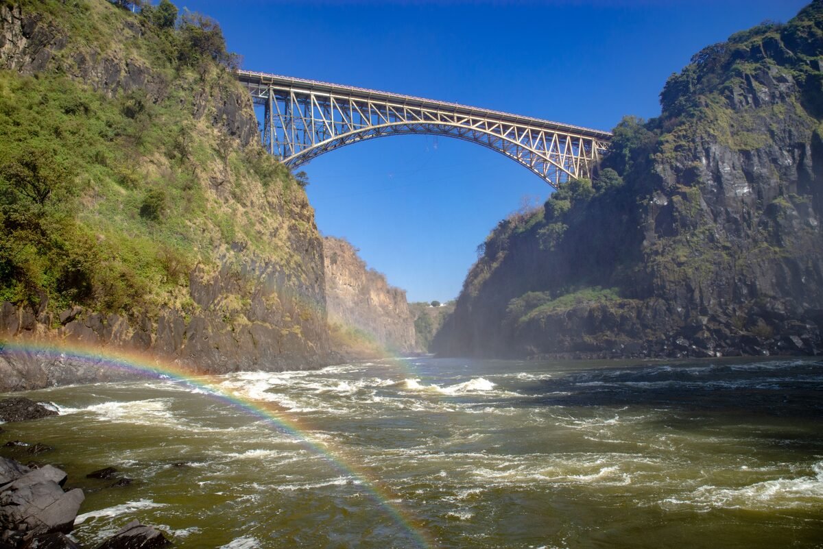 Victoria Falls Bridge arching over the Batoka Gorge with rainbow, viewed from Zambia side, Livingstone