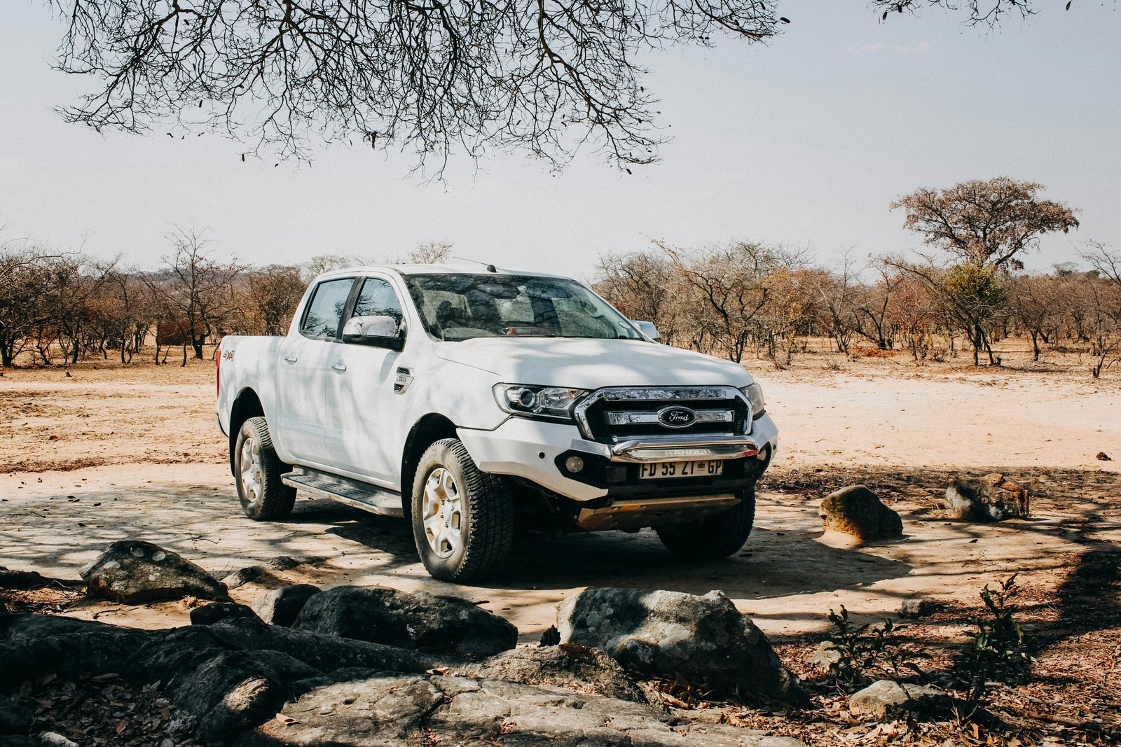 White Ford Ranger 4x4 pickup truck parked in Zimbabwean bush savanna